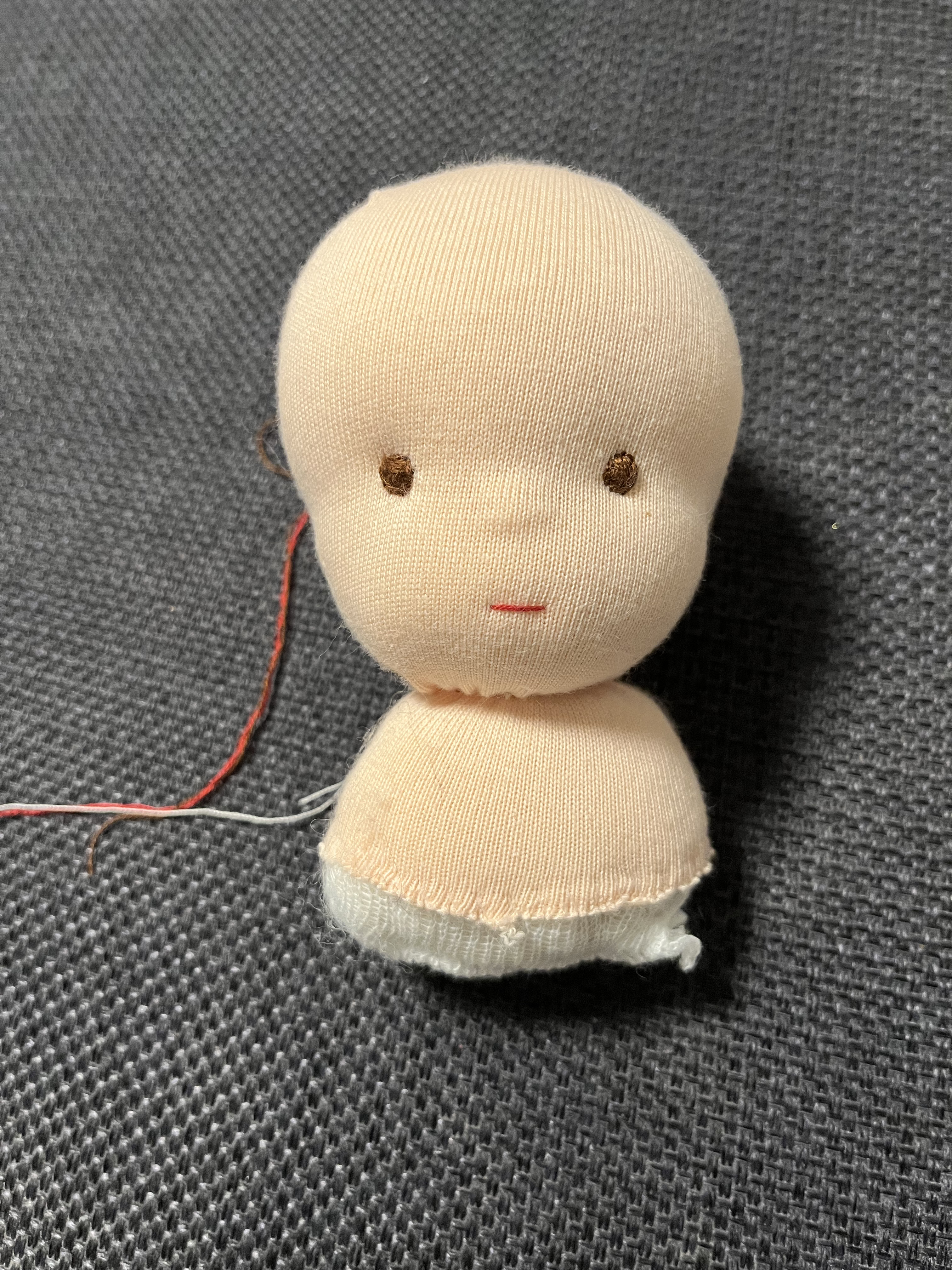 Person hand-stitching a soft doll