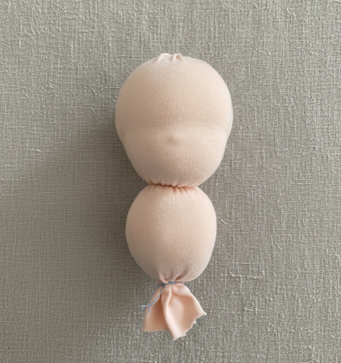 Person hand-stitching a soft doll